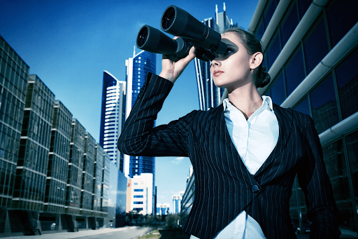 Woman in a city looking through binoculars.